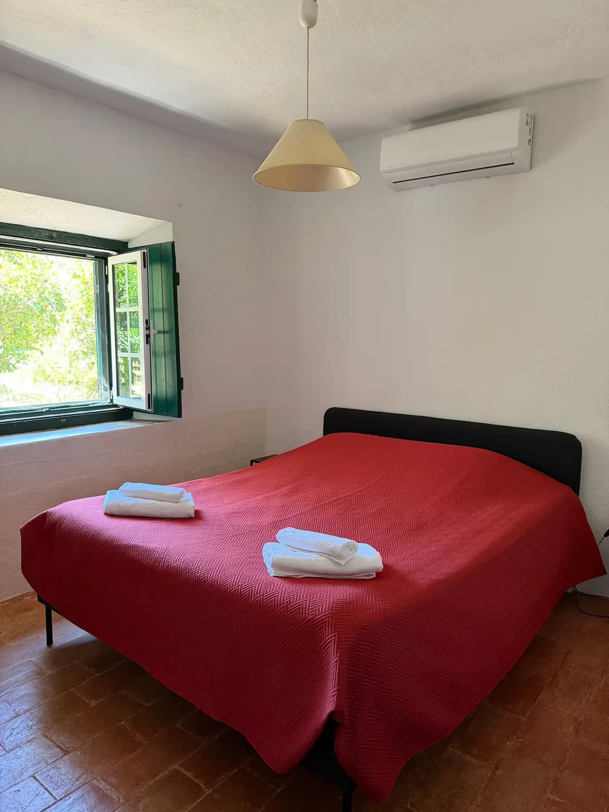 Double bedroom with a red bedspread and a window onto the garden